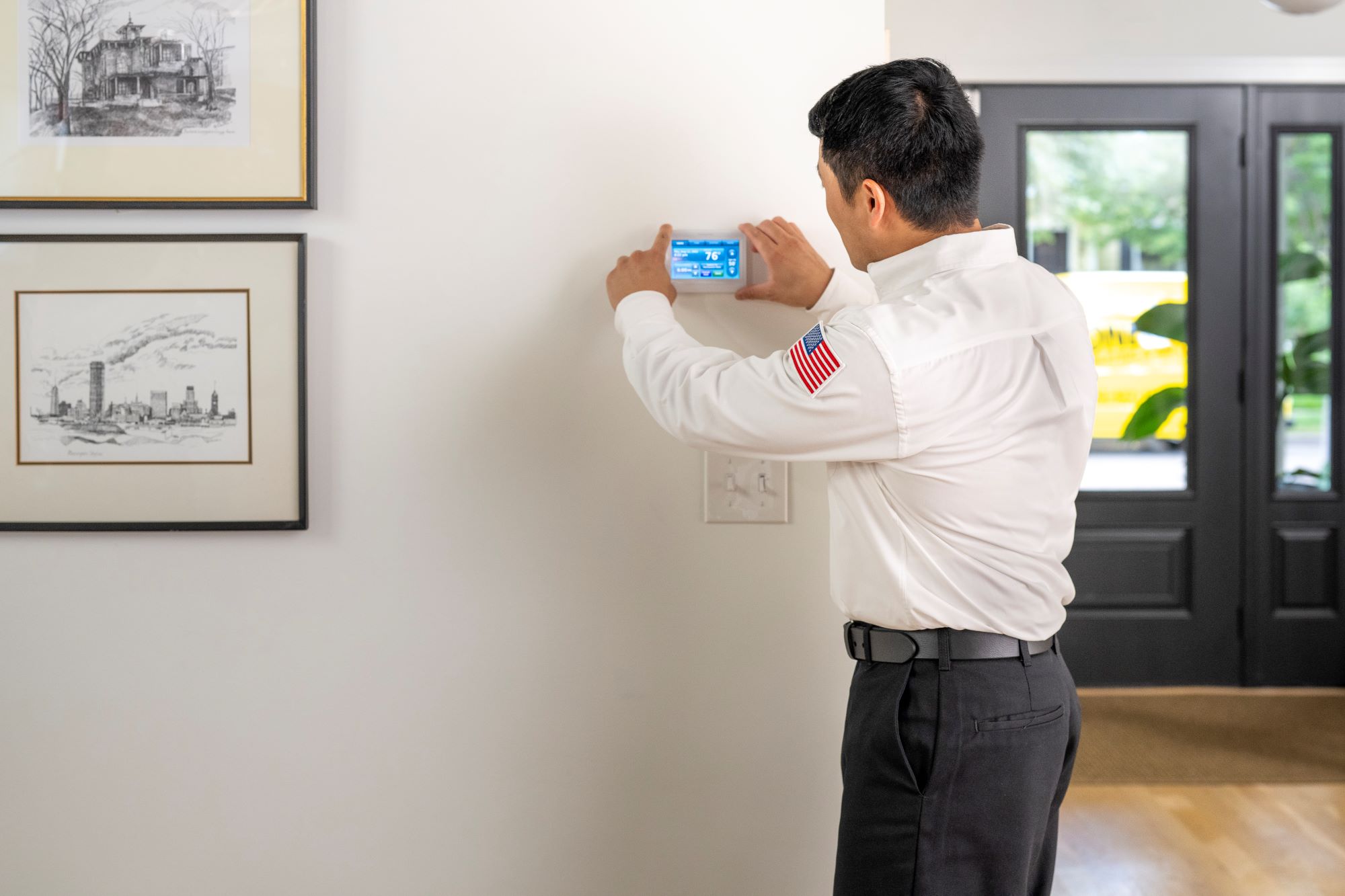 One Hour technician operating HVAC technology with a digital thermostat.